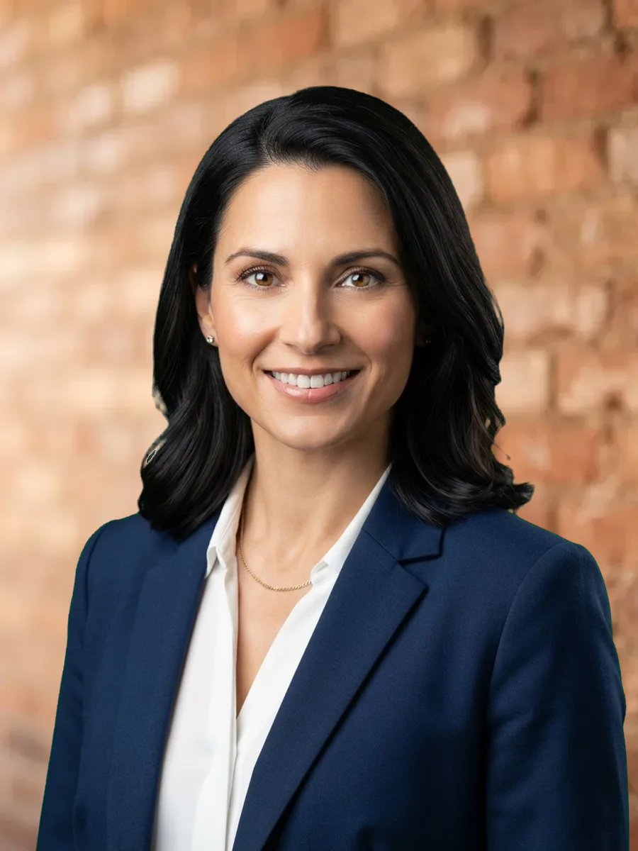 The same headshot in front of an exposed brick wall